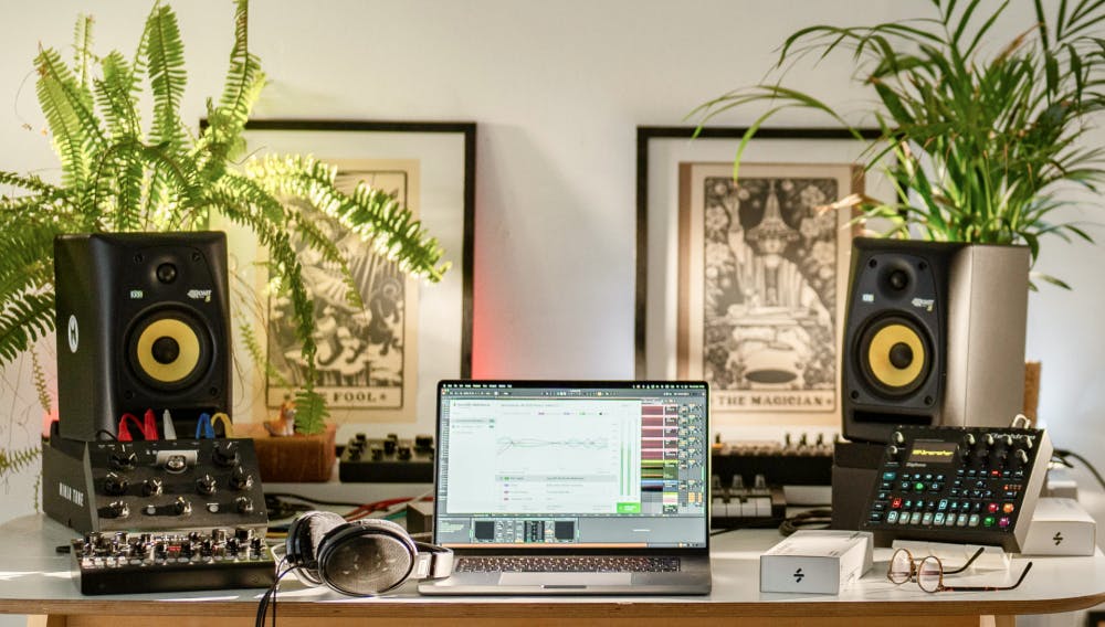 Well-lit home studio setup featuring KRK monitors, SoundID Reference software on a laptop screen, analog gear, headphones, and plants